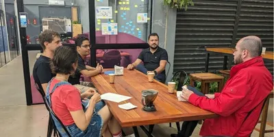 Mentoria em volta de uma mesa, com seis pessoas conversando